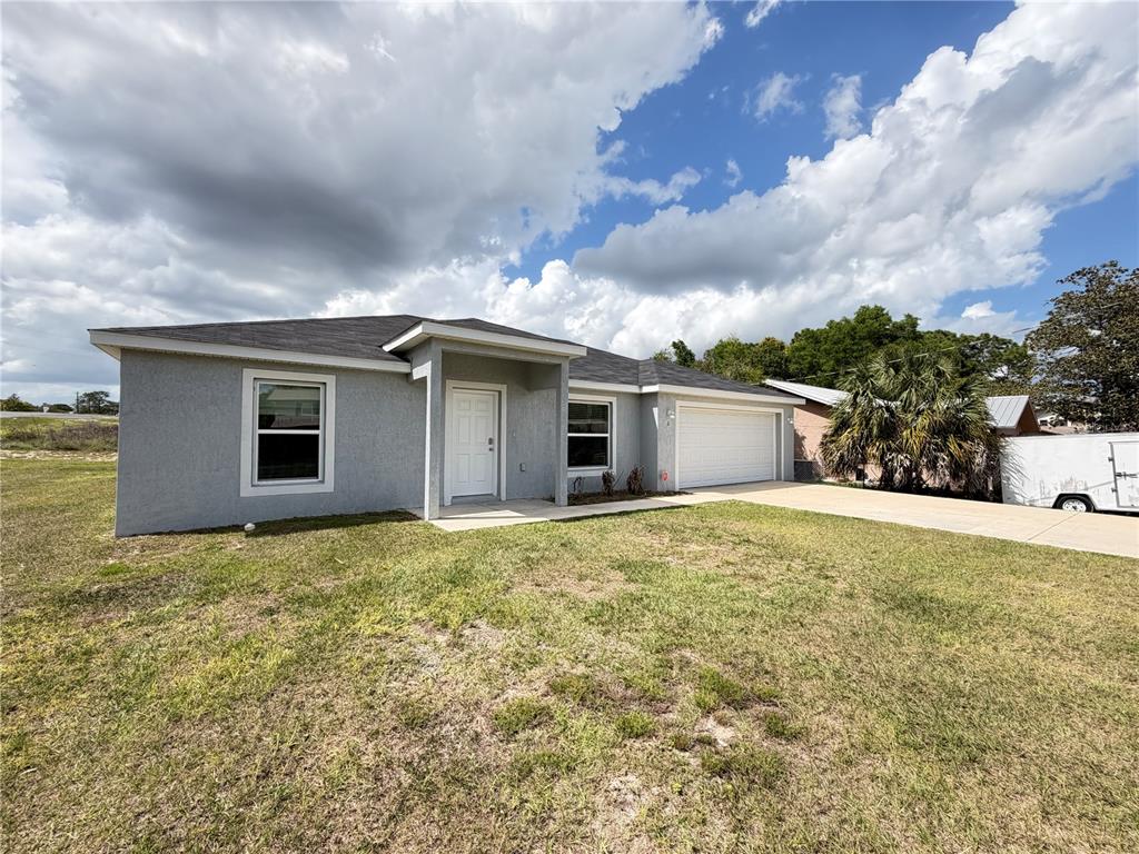 A single-story gray stucco house with a white front door and a two-car garage — 2 BAHIA COURT RUN, OCALA, FL