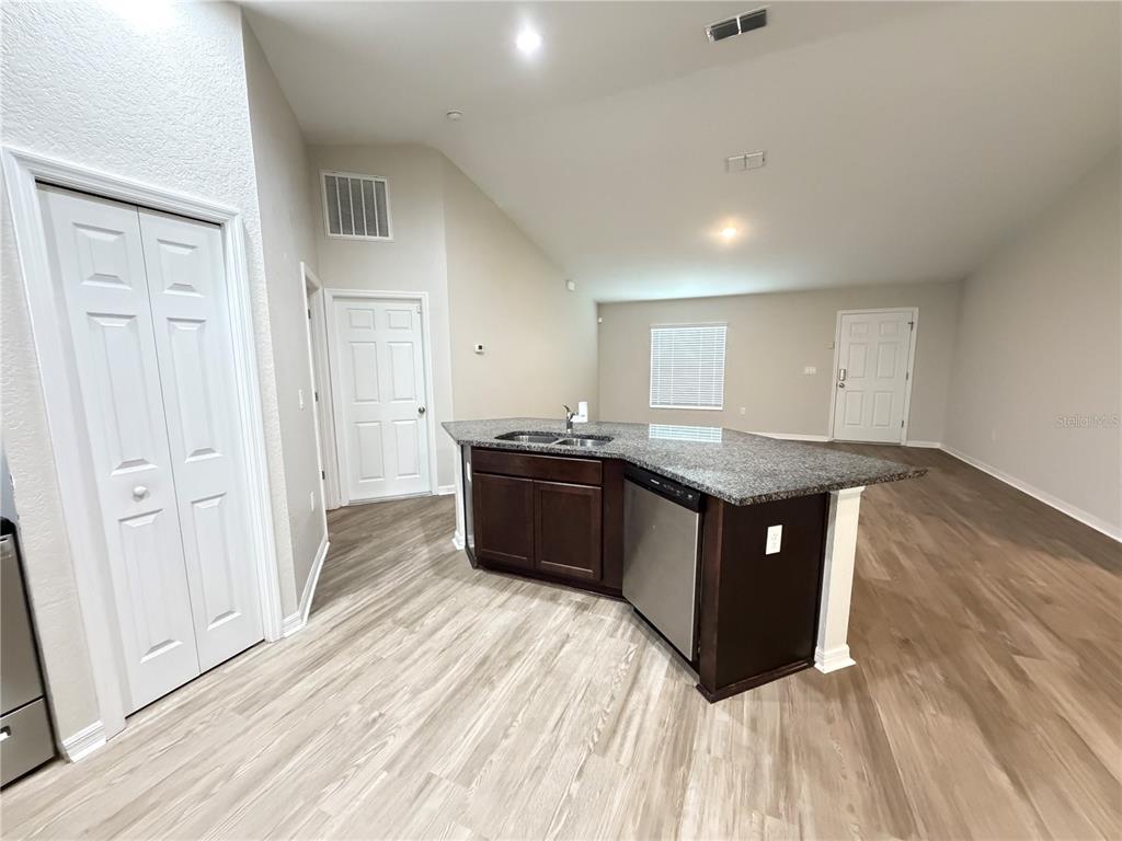 A kitchen island with granite countertops and stainless steel appliances sits in an open room — 2 BAHIA COURT RUN, OCALA, FL