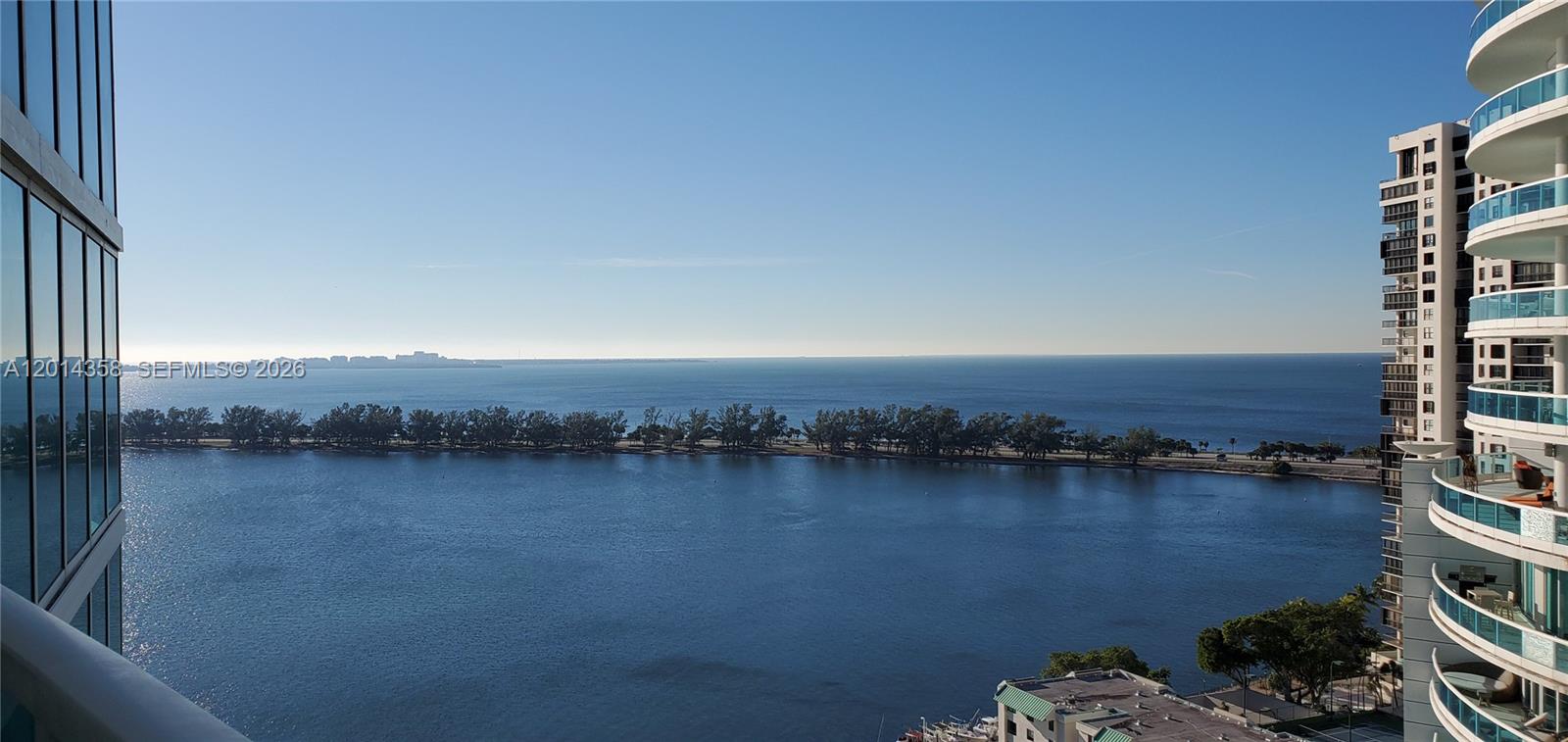 A high-angle view shows a bay, a tree-lined causeway, and surrounding high-rise apartment buildings — 2101 Brickell Ave # 1808, Miami FL 33129, MIAMI, FL