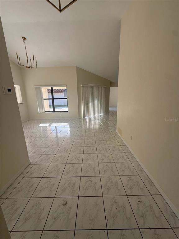 An open-concept living area features vaulted ceilings, white tile flooring, and a sliding glass door — 8102 S IBIZA COURT, ORLANDO, FL