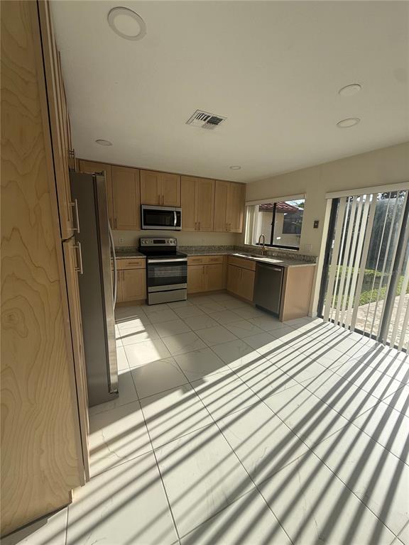 A kitchen with light wood cabinets, stainless steel appliances, and white tiled floors — 8102 S IBIZA COURT, ORLANDO, FL