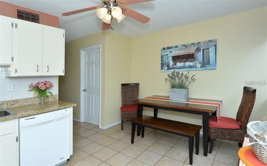 A kitchen and dining area with tile floors, white cabinets, and a wooden table — 2946 CLARK ROAD UNIT 2946, SARASOTA, FL