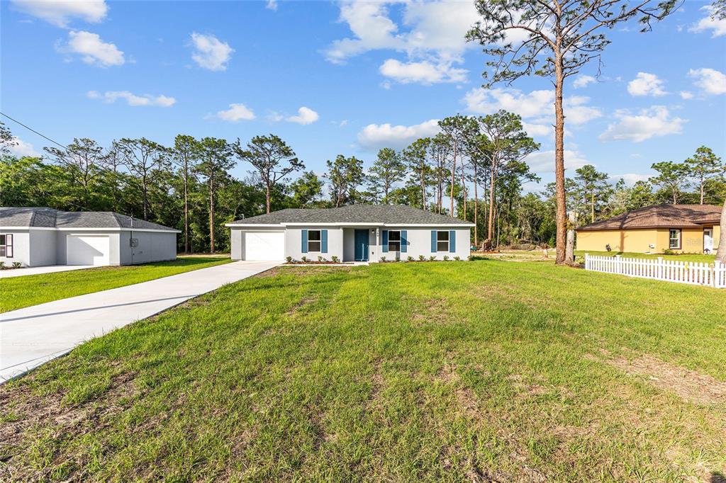A single-story gray house with blue shutters and a concrete driveway sits on a lawn — 360 LOCUST ROAD, OCALA, FL