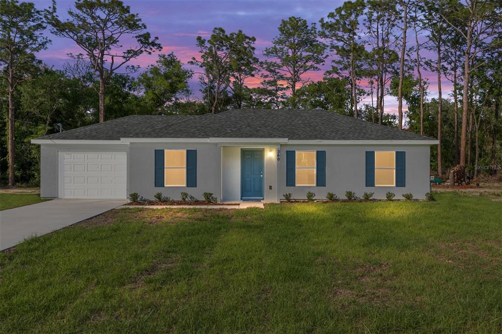 A single-story gray house with a blue door, white garage, and dark shutters — 360 LOCUST ROAD, OCALA, FL