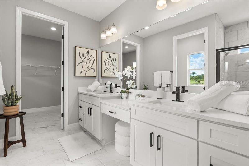 A bright bathroom features a double vanity with white cabinets, marble floors, and a walk-in closet — 2665 SW 162 LANE, OCALA, FL