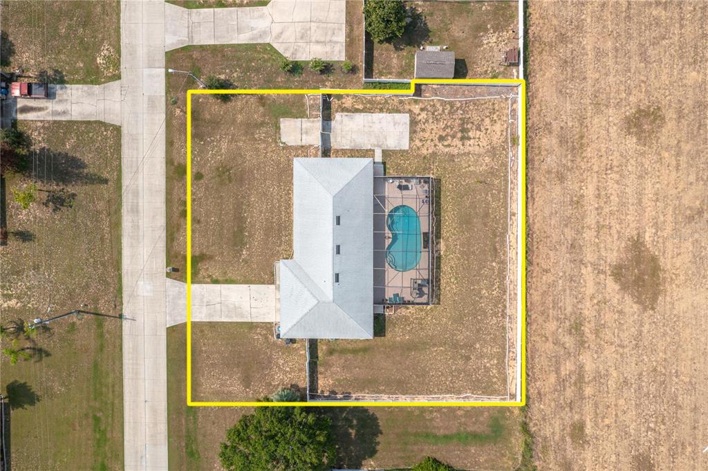 An aerial view shows a house with a screened-in pool and a fenced backyard — 411 COUNTRY PINE ROAD, HAINES CITY, FL