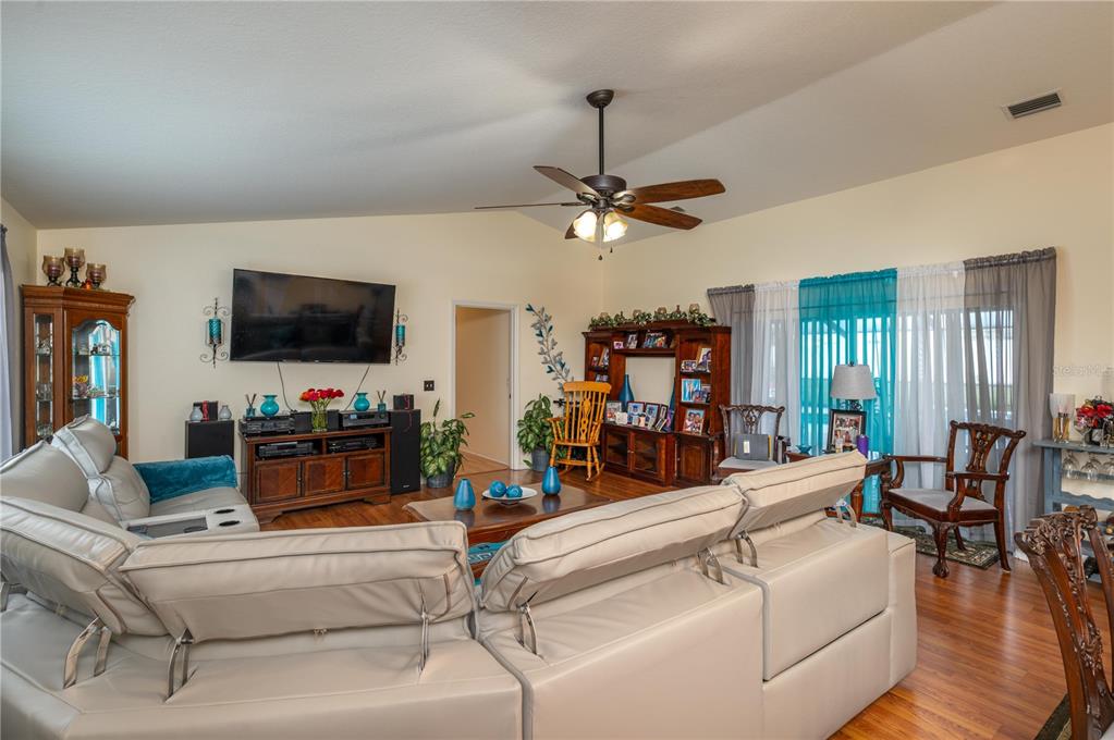 A living room features a large sectional sofa, a television, and wood-look flooring — 411 COUNTRY PINE ROAD, HAINES CITY, FL
