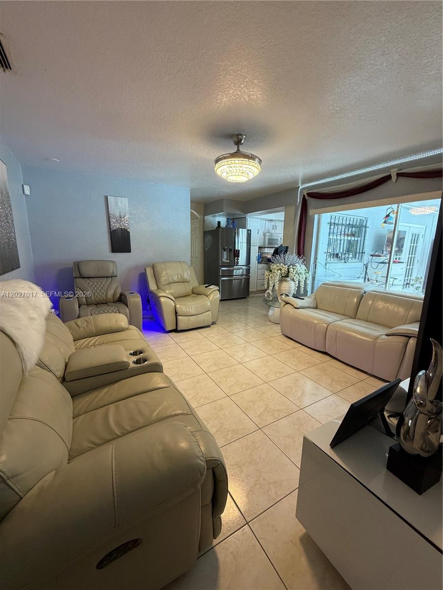 A living room features light-colored tile floors, leather furniture, and a ceiling fan — 4162 Kingsbridge Drive, Orlando FL 32839, ORLANDO, FL