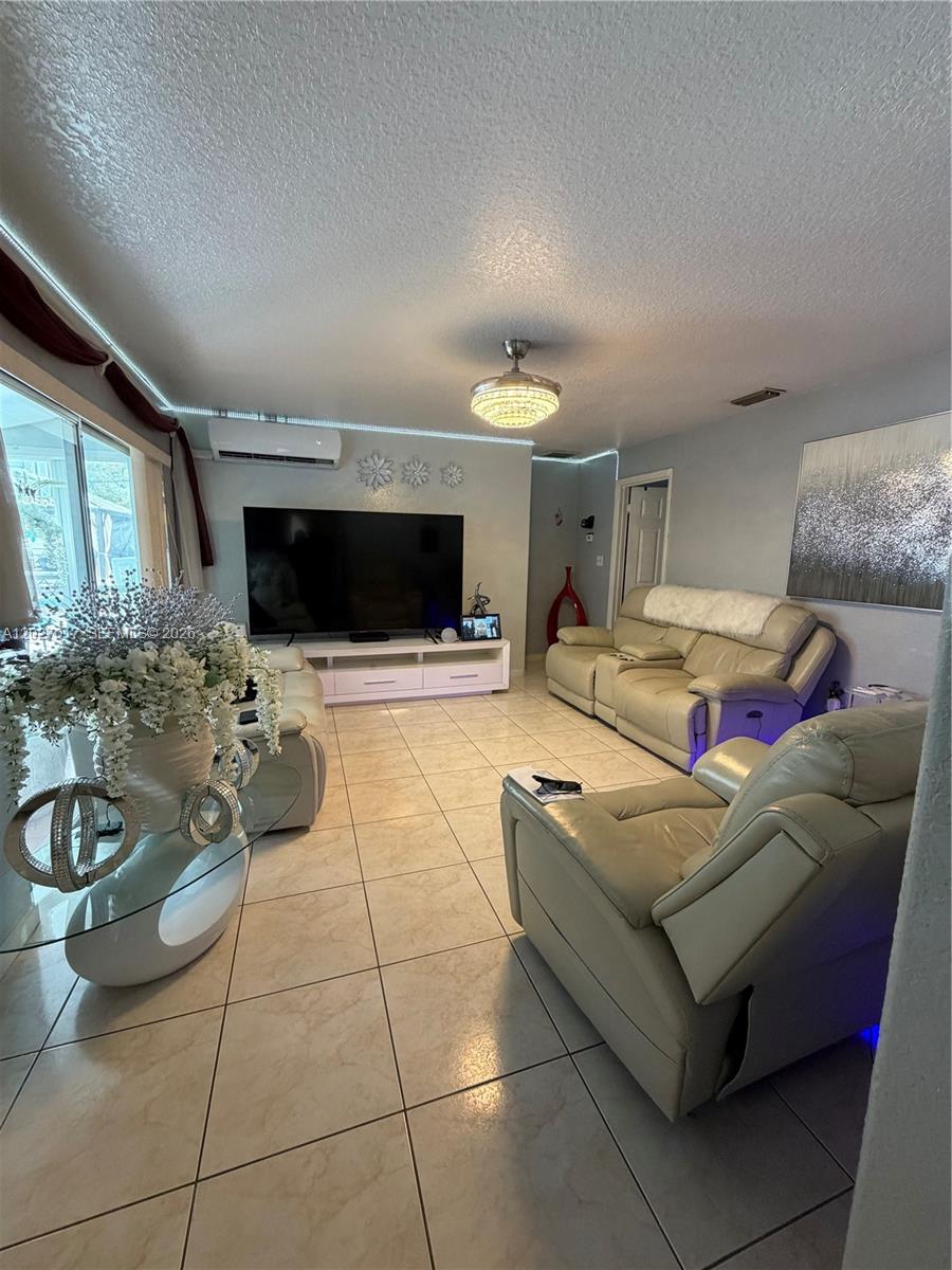 A living room features light tile flooring, leather reclining furniture, a large television, and LED lighting — 4162 Kingsbridge Drive, Orlando FL 32839, ORLANDO, FL