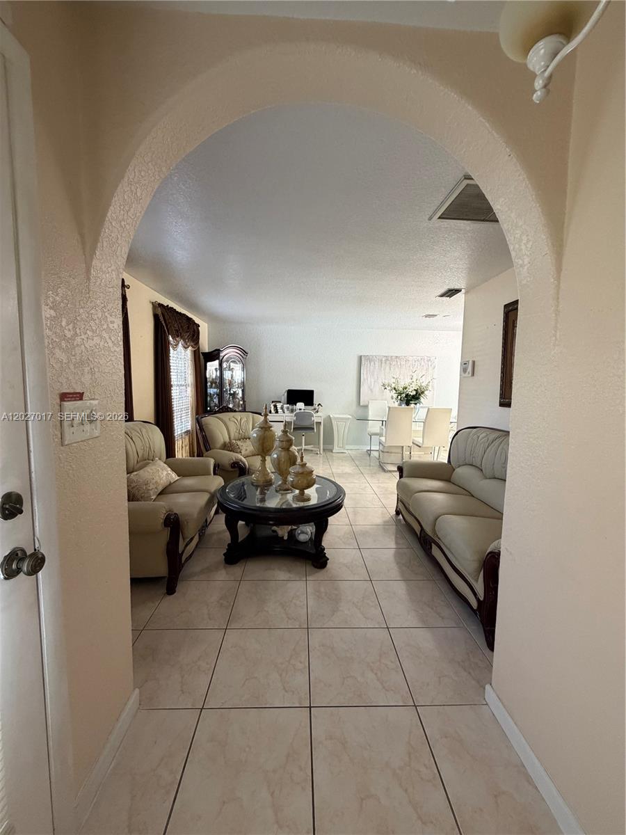 An arched entryway leads into a living room with tile flooring and cream-colored furniture — 4162 Kingsbridge Drive, Orlando FL 32839, ORLANDO, FL