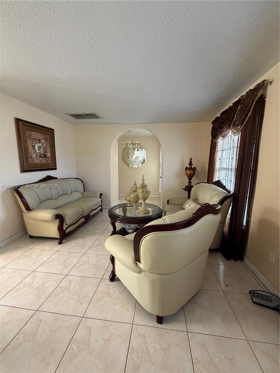 A living room features cream-colored leather furniture, a glass coffee table, and tile flooring — 4162 Kingsbridge Drive, Orlando FL 32839, ORLANDO, FL