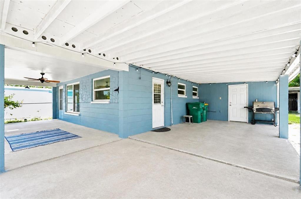 A blue house features a large covered concrete patio with string lights and a grill — 8042 91ST TERRACE, SEMINOLE, FL