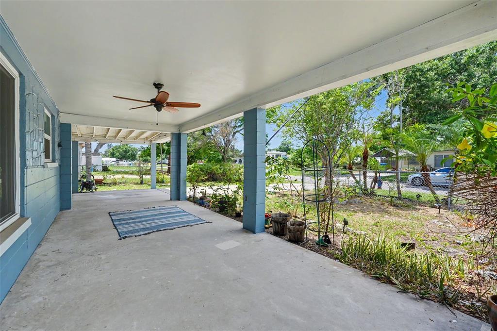 A covered concrete patio features blue support pillars, a ceiling fan, and a striped rug — 8042 91ST TERRACE, SEMINOLE, FL