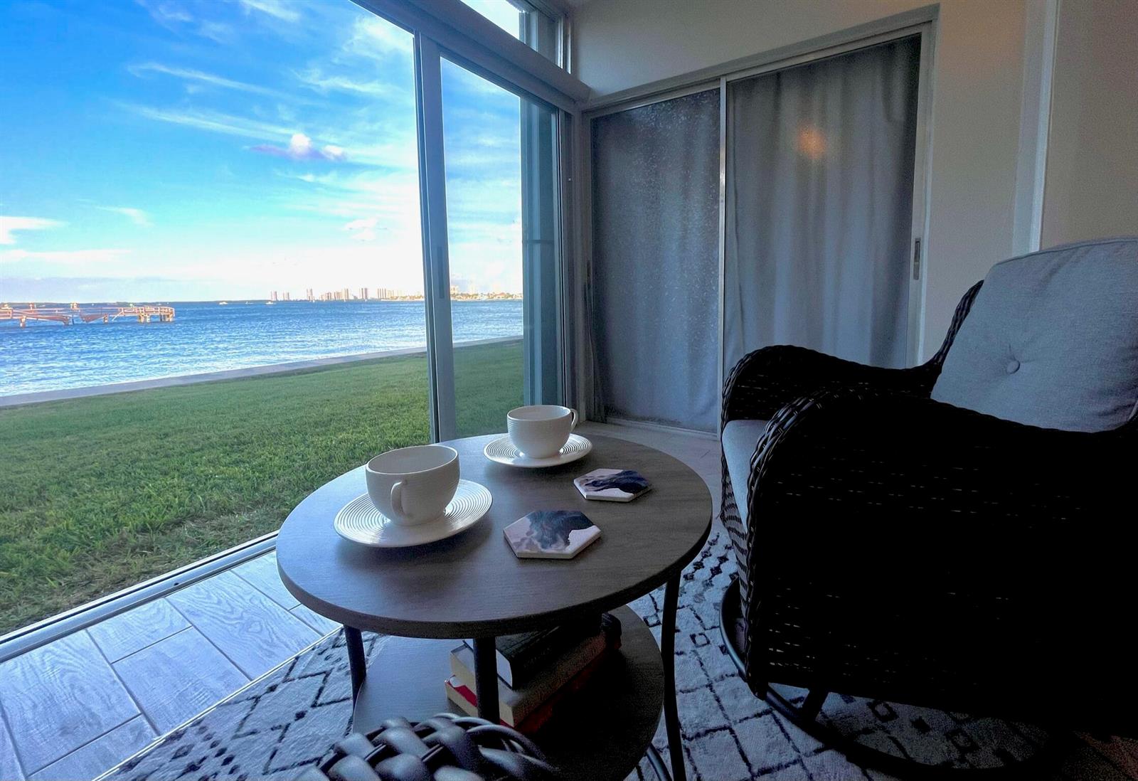 A room with a round table, two chairs, and a sliding door overlooking the water — 410 Wilma Circle # 103, Riviera Beach FL 33404, RIVIERA BEACH, FL