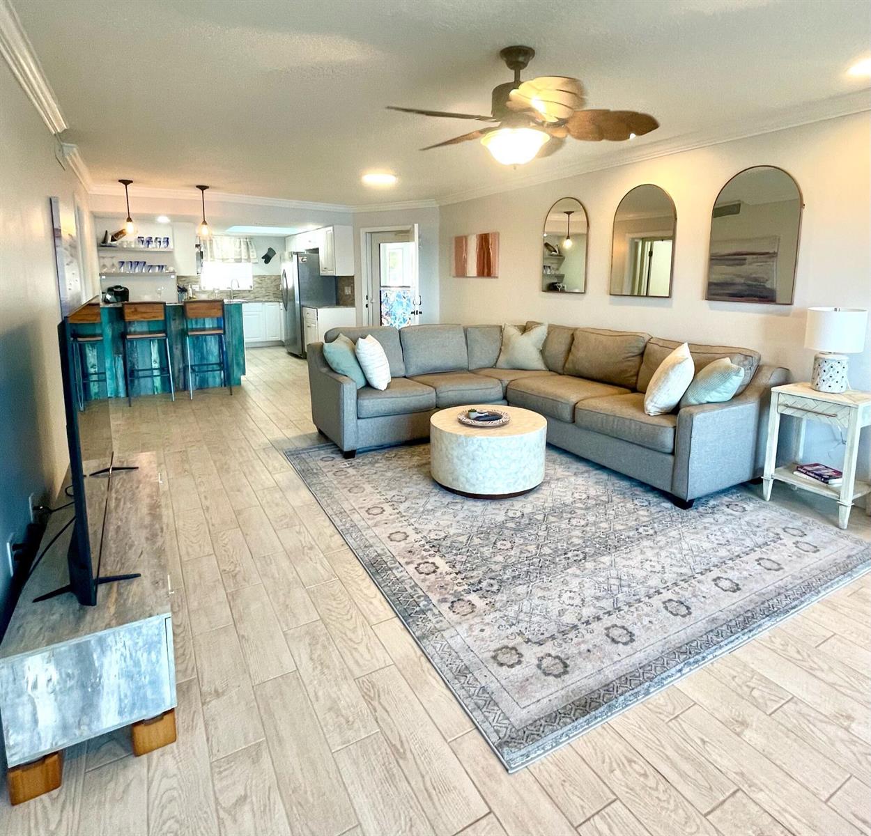 A living room with a sectional sofa, round coffee table, and an open kitchen area — 410 Wilma Circle # 103, Riviera Beach FL 33404, RIVIERA BEACH, FL