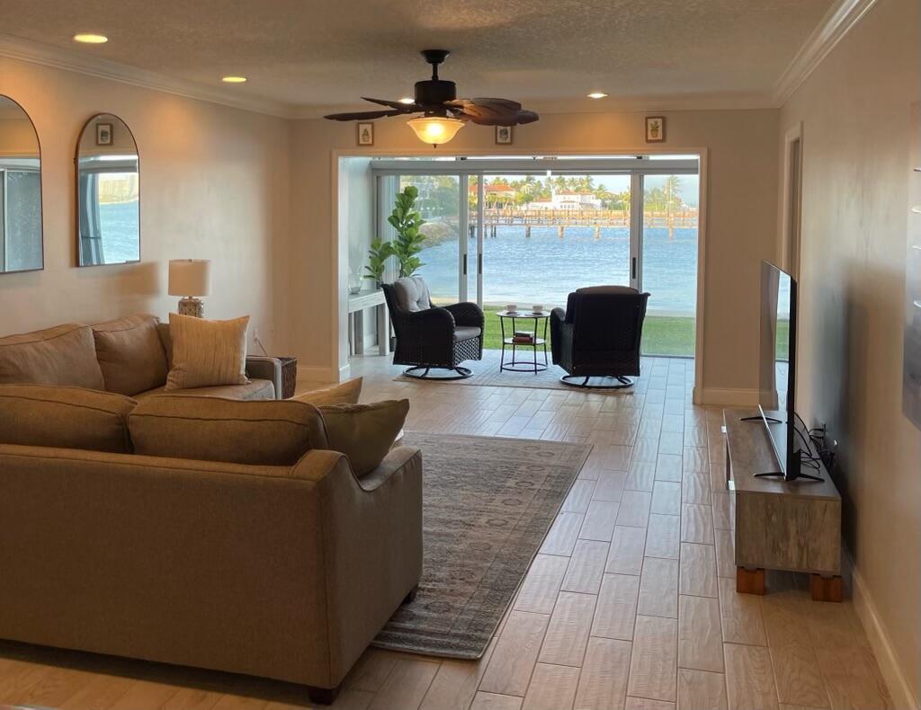 A living room with tile floors, a sectional sofa, and sliding doors overlooking a waterfront view — 410 Wilma Circle # 103, Riviera Beach FL 33404, RIVIERA BEACH, FL
