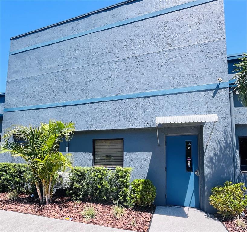 A blue exterior wall features a single door with an awning and a small window — 6935 RIDGE ROAD, PORT RICHEY, FL