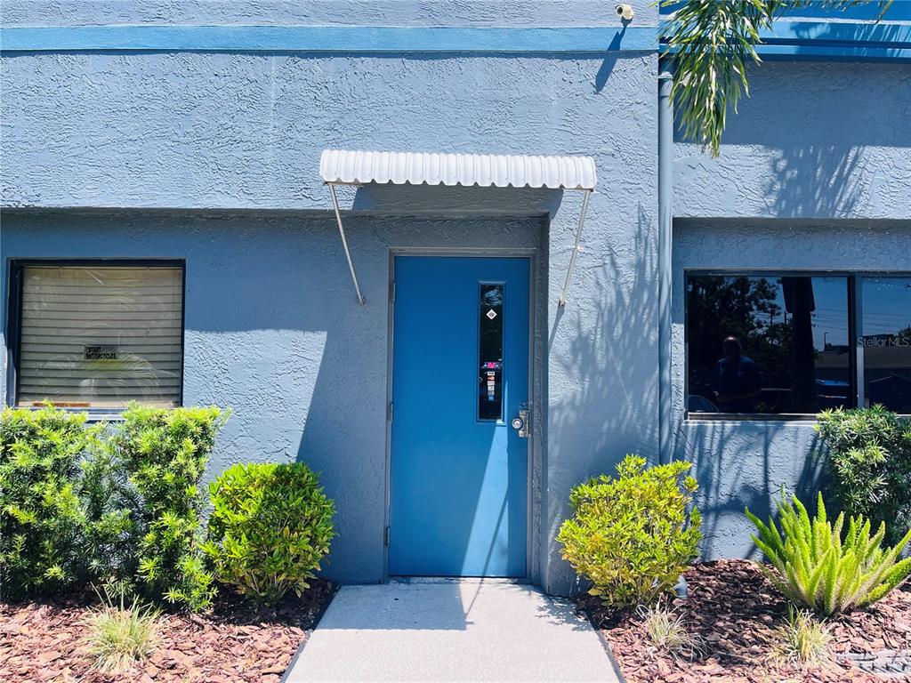 The exterior of a blue building features a central door with an awning and windows — 6935 RIDGE ROAD, PORT RICHEY, FL
