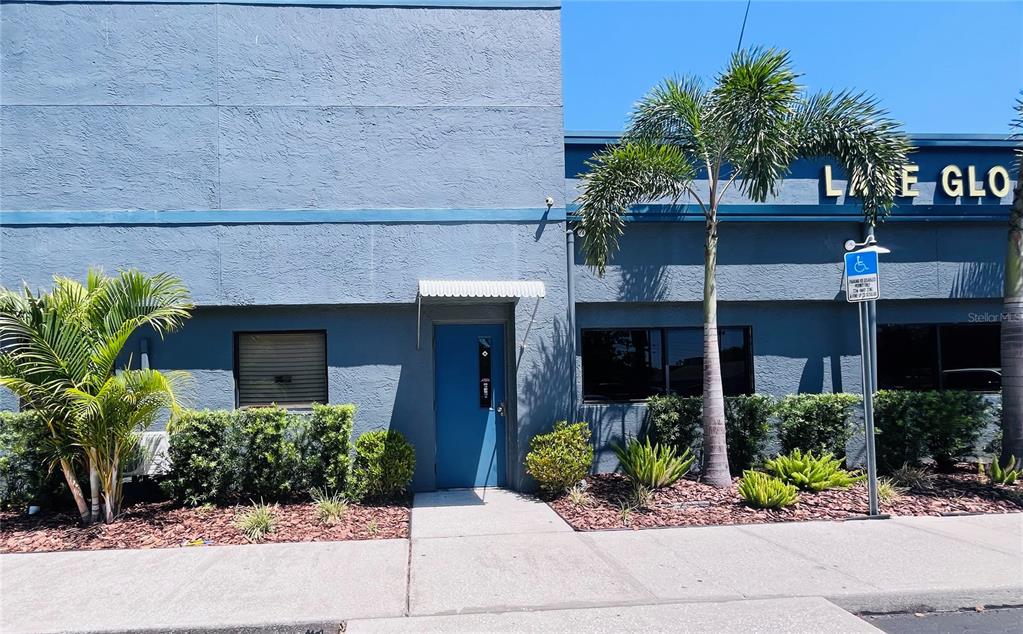 A blue commercial building exterior features a central door, palm trees, and a handicap sign — 6935 RIDGE ROAD, PORT RICHEY, FL