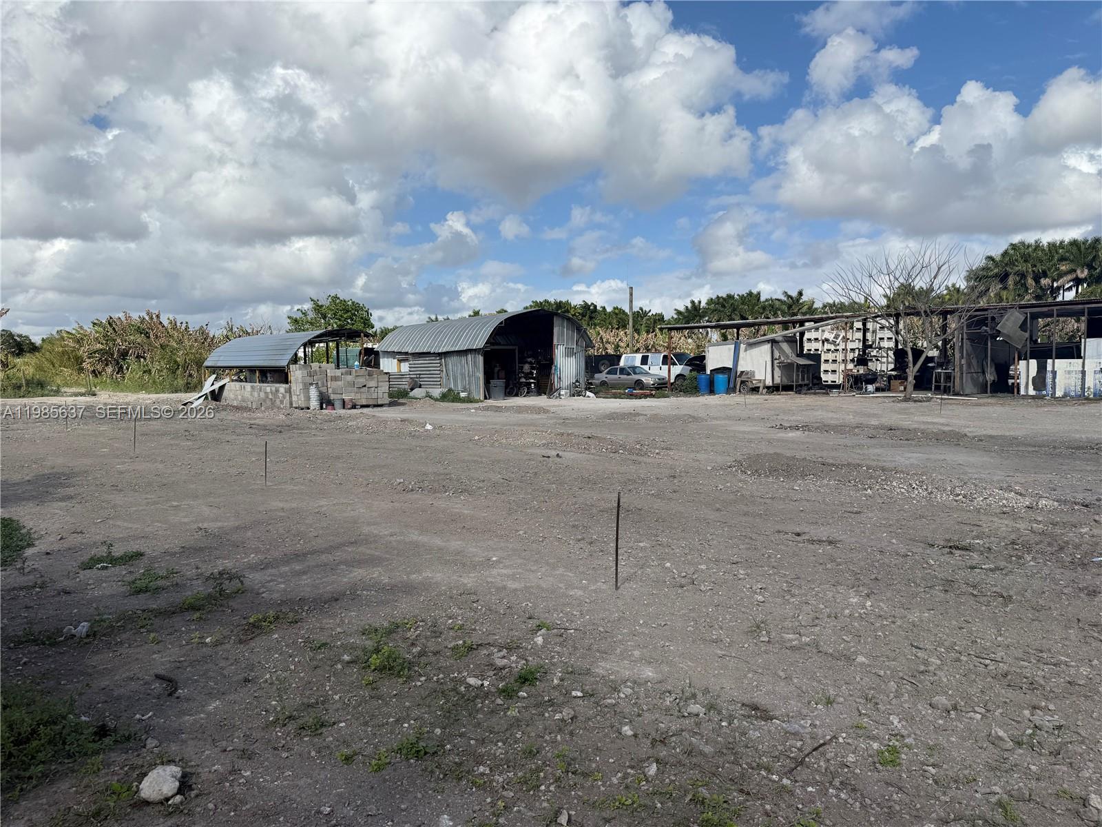 An open dirt lot features several metal storage sheds and structures under a cloudy sky — 16455 SW 207, Homestead FL 33187, HOMESTEAD, FL