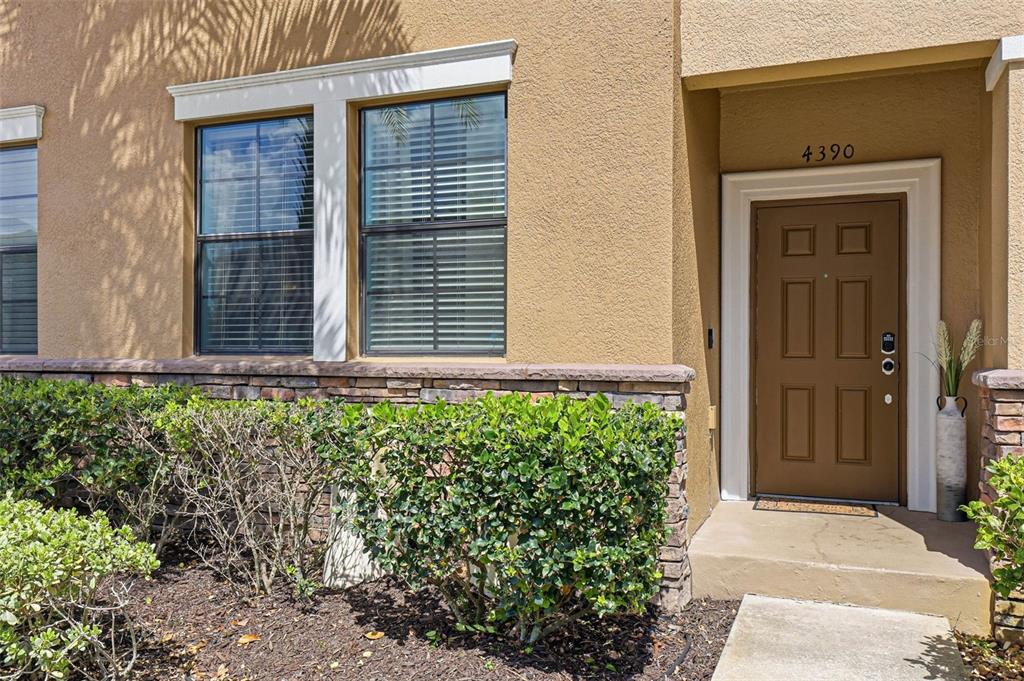 The exterior of a tan stucco home features a brown front door and stone siding — 4390 FENNWOOD COURT, WESLEY CHAPEL, FL