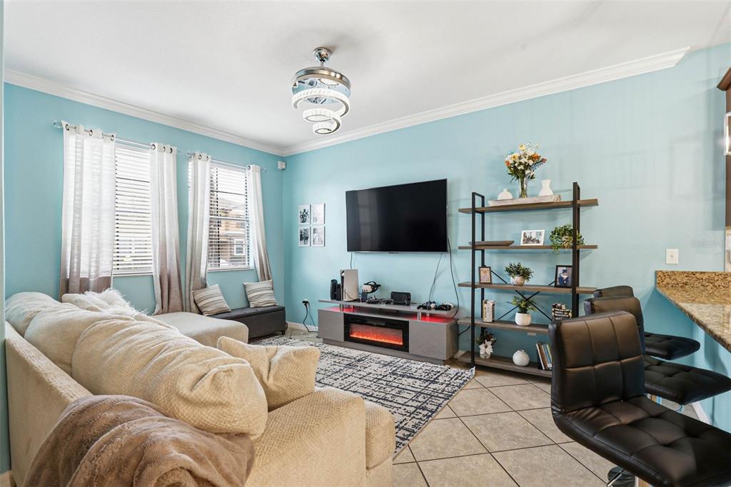 A living room with light blue walls, a beige sofa, a television, and a bookshelf — 4390 FENNWOOD COURT, WESLEY CHAPEL, FL