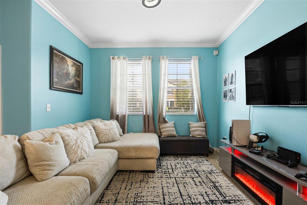 A living room features light blue walls, a beige sectional sofa, and a fireplace console — 4390 FENNWOOD COURT, WESLEY CHAPEL, FL