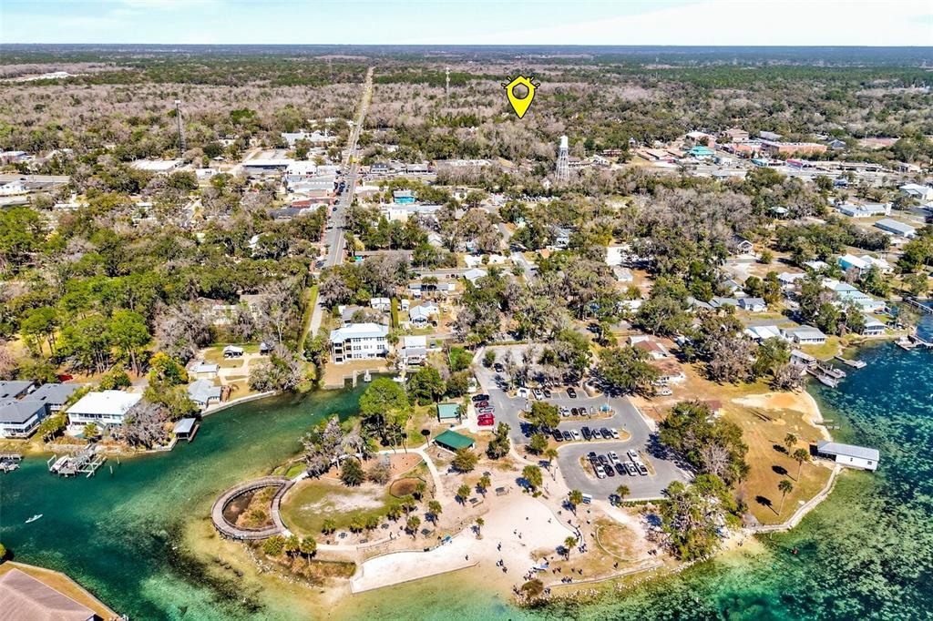 This aerial view shows a waterfront park with a parking lot and nearby town buildings — 110 NE CRYSTAL STREET, CRYSTAL RIVER, FL
