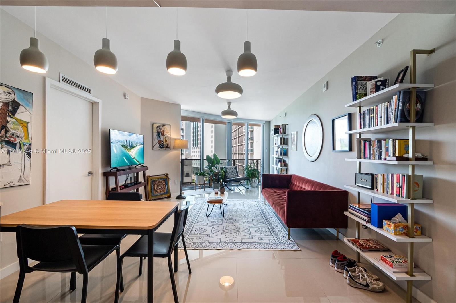 A modern living and dining area features a red sofa, white shelving, and pendant lighting — 488 NE 18th St # 401, Miami FL 33132, MIAMI, FL