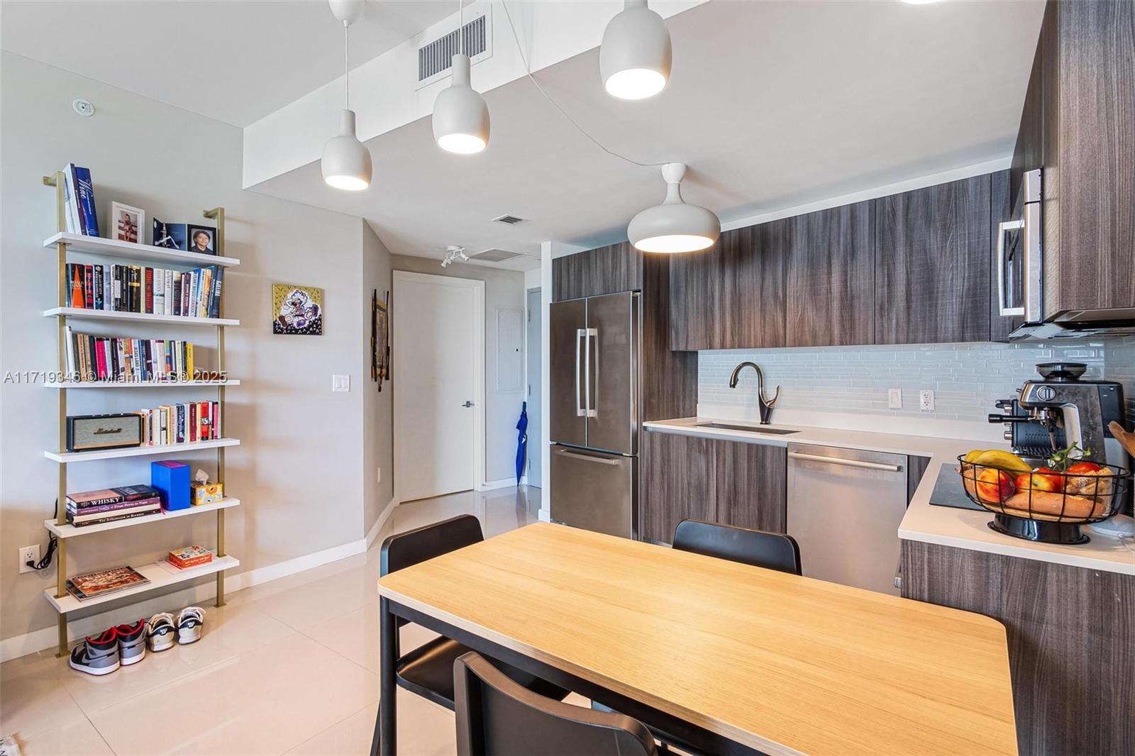 A modern kitchen features dark wood cabinets, stainless steel appliances, and an adjacent dining area — 488 NE 18th St # 401, Miami FL 33132, MIAMI, FL