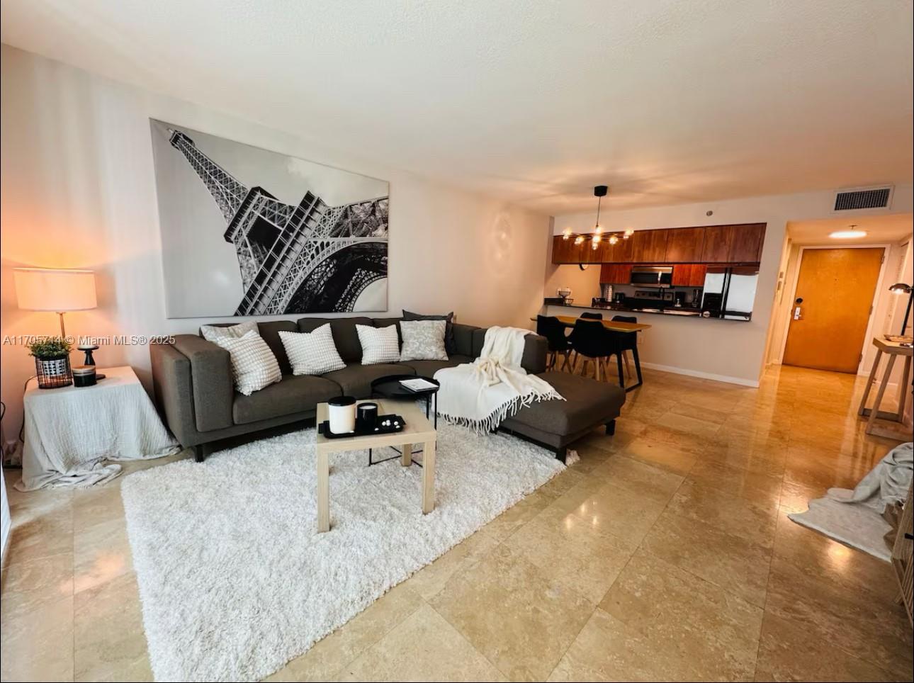 A living room with a grey sectional sofa, white rug, and an open kitchen area — 1200 Brickell Bay Dr # 3220, Miami FL 33131, MIAMI, FL