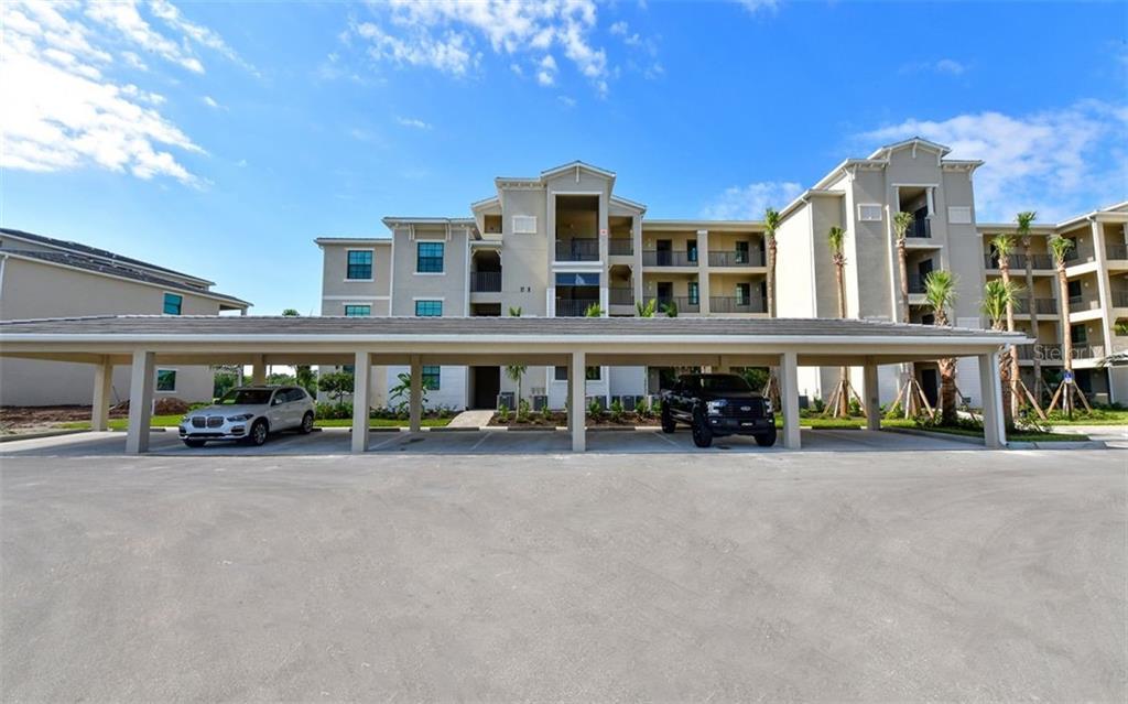 A multi-story apartment building with a covered parking structure in the foreground — 17520 GAWTHROP DRIVE UNIT 203, LAKEWOOD RANCH, FL
