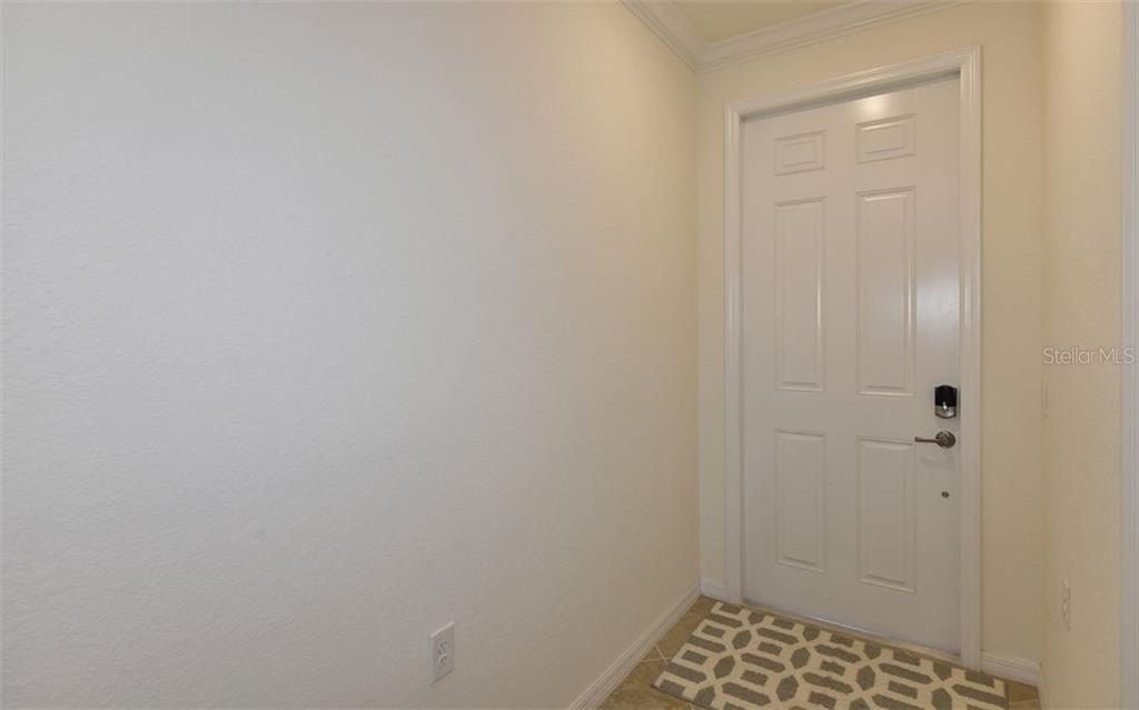 A white door with a smart lock opens into a small entryway with tiled flooring — 17520 GAWTHROP DRIVE UNIT 203, LAKEWOOD RANCH, FL