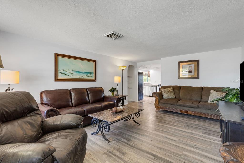 A living room features wood-look flooring, a leather sofa, a fabric sofa, and a coffee table — 979 KIMBALL ROAD, VENICE, FL