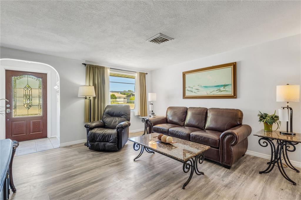 A living room features light wood-look flooring, a brown leather sofa, and a recliner — 979 KIMBALL ROAD, VENICE, FL