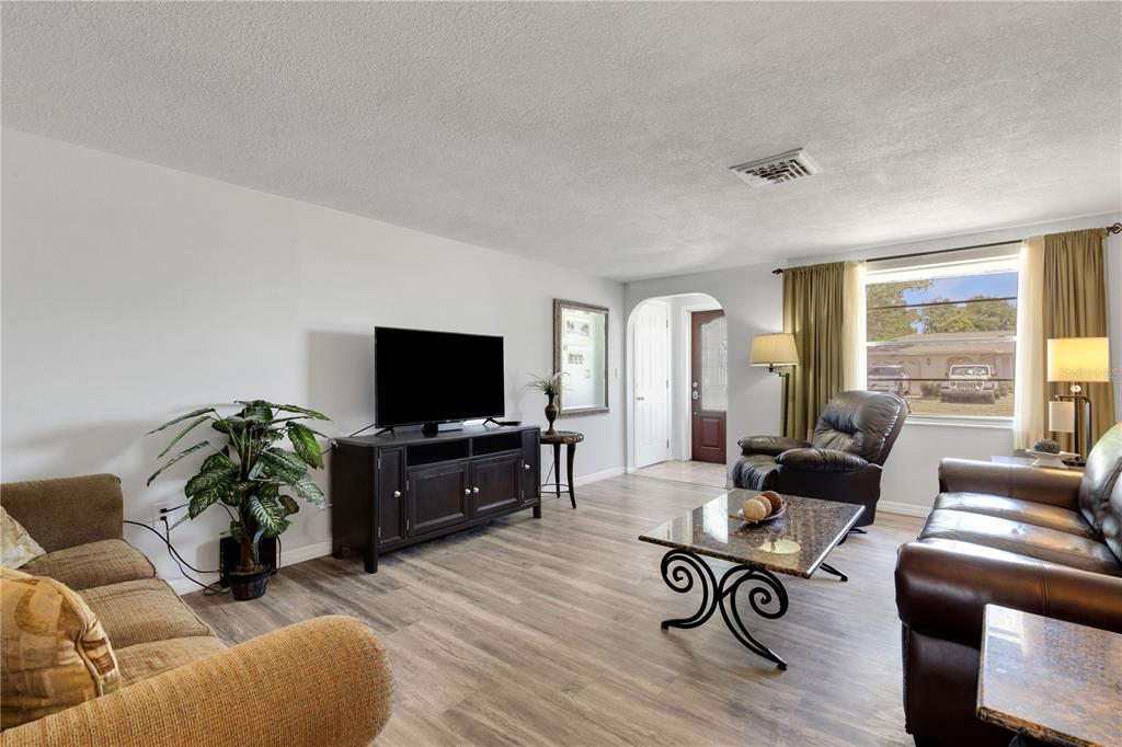 A living room features light wood-look flooring, a television on a console, and leather furniture — 979 KIMBALL ROAD, VENICE, FL