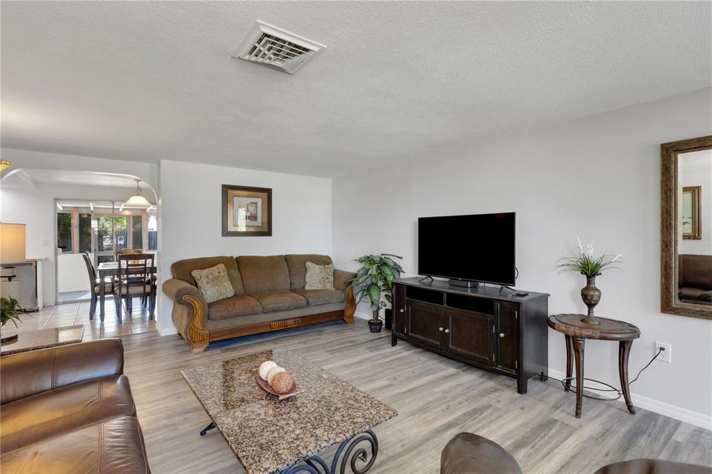 A living room features light wood-look flooring, a brown sofa, a television console, and a coffee table — 979 KIMBALL ROAD, VENICE, FL