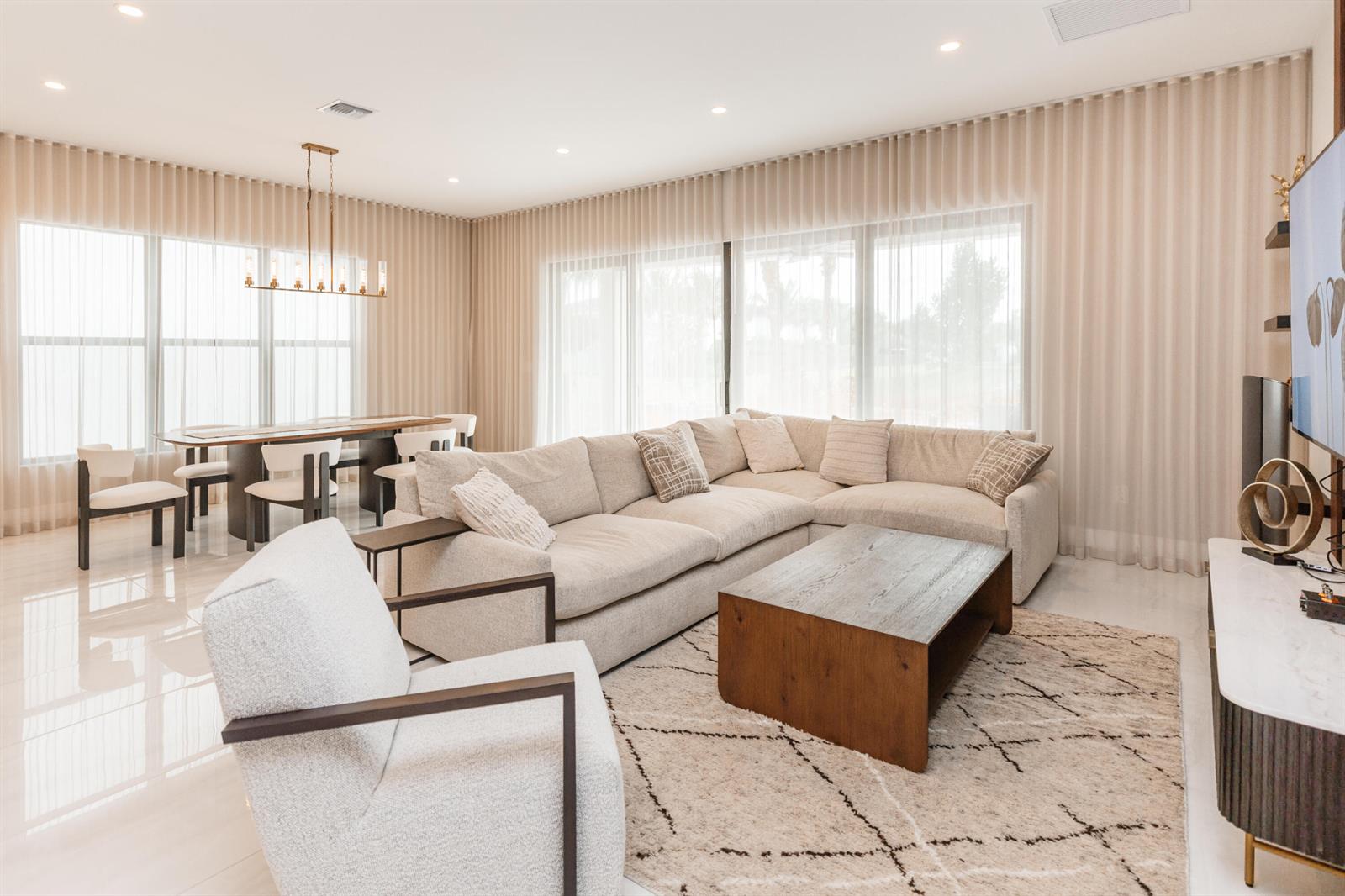A bright living and dining area features a sectional sofa, coffee table, and floor-to-ceiling curtains — 8606 Tower Bridge Court, Boca Raton FL 33496, BOCA RATON, FL