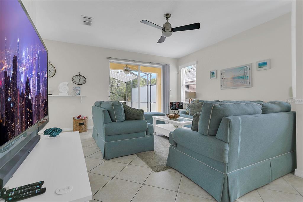 A living room features light blue sofas, a white coffee table, and a large television — 178 HAMMOCK COURT, DAVENPORT, FL