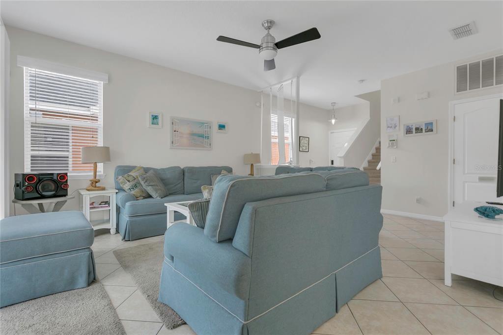 A living room features light blue sofas, tile flooring, a ceiling fan, and a staircase — 178 HAMMOCK COURT, DAVENPORT, FL