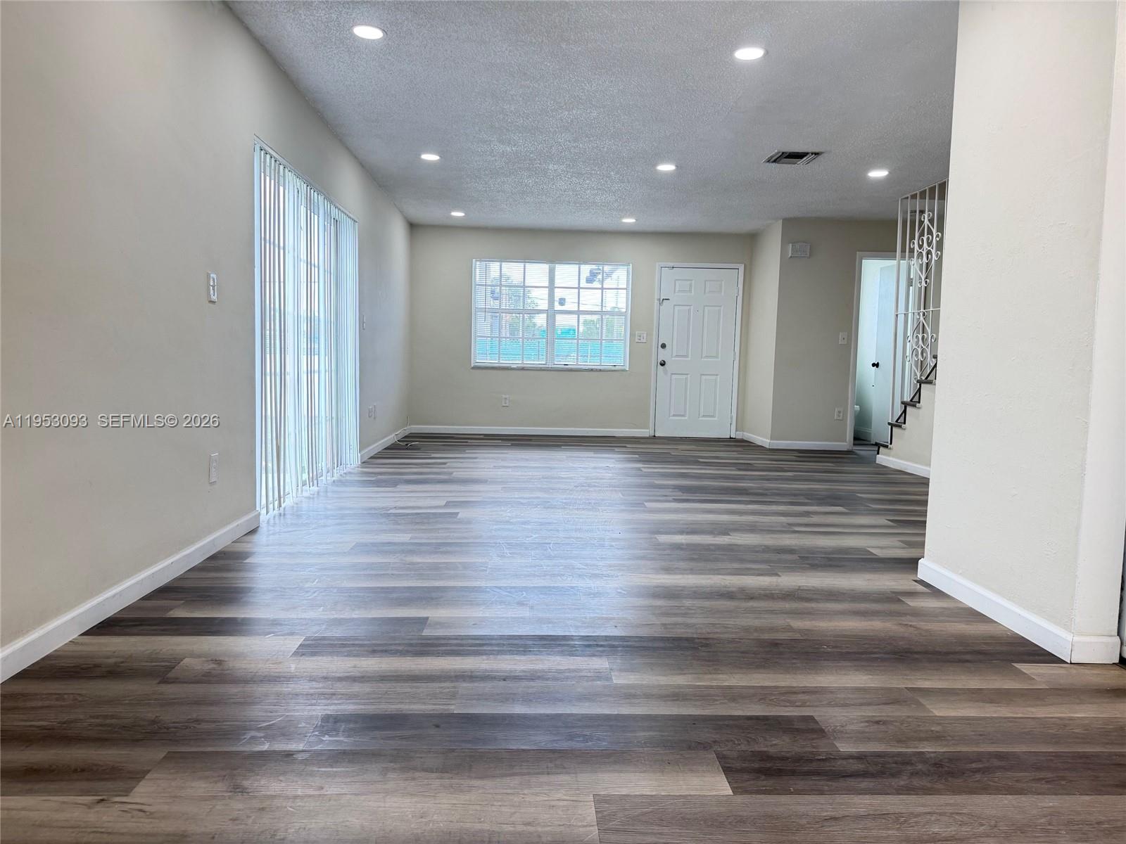 An empty living room features light-colored walls, recessed lighting, and wood-look vinyl plank flooring — 9503 SW 88th Ter # 9503, Miami FL 33176, MIAMI, FL