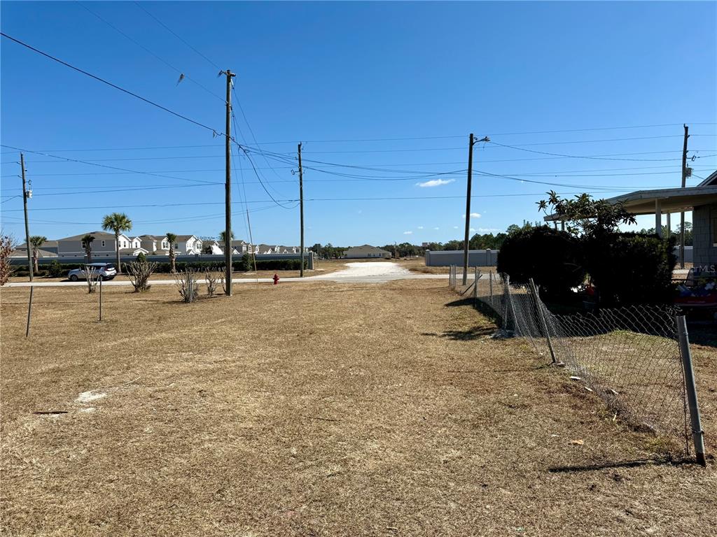 A vacant, grassy lot sits between a chain-link fence and utility poles under a clear sky — CHURCH STREET, UMATILLA, FL