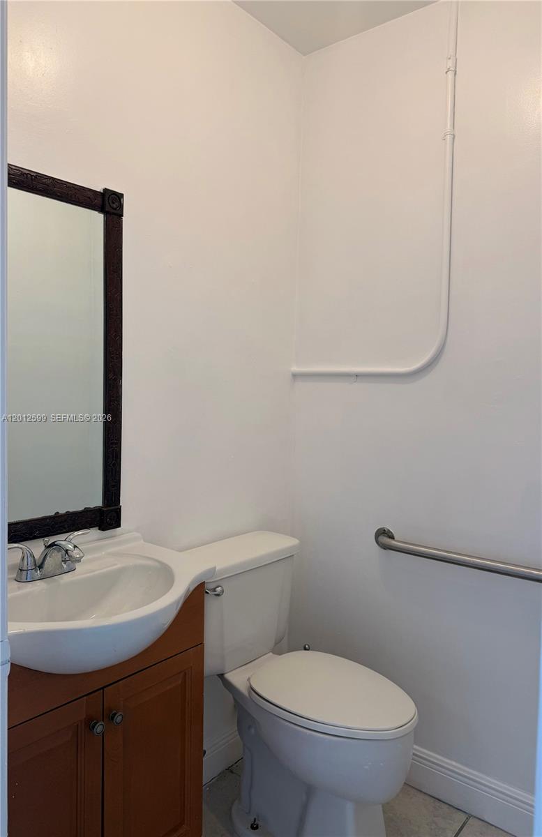 A small bathroom features a vanity with a mirror, a toilet, and a grab bar — 12311 SW 133rd Ct # 23, Miami FL 33186, MIAMI, FL