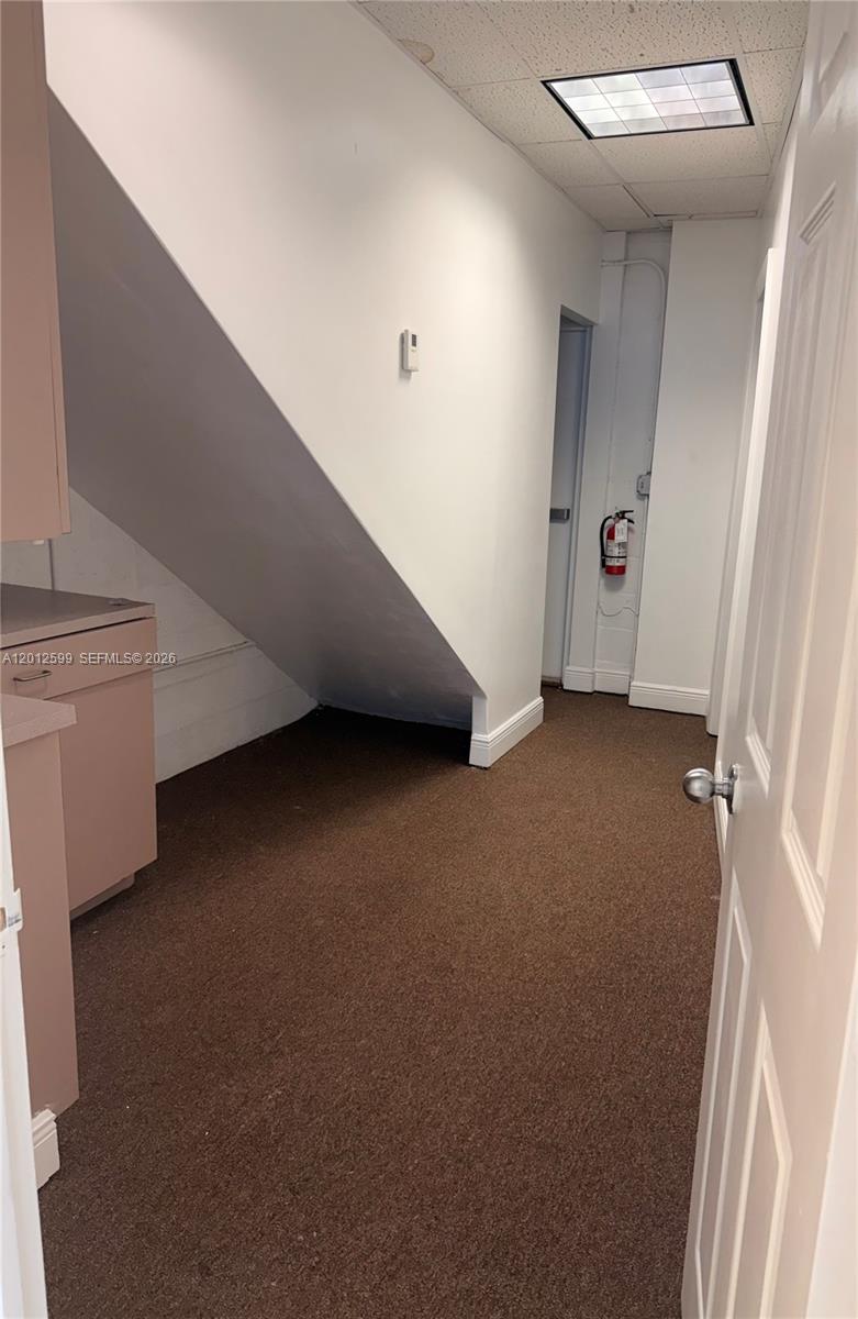 This interior space features brown carpeting, a sloped ceiling, and a fire extinguisher — 12311 SW 133rd Ct # 23, Miami FL 33186, MIAMI, FL