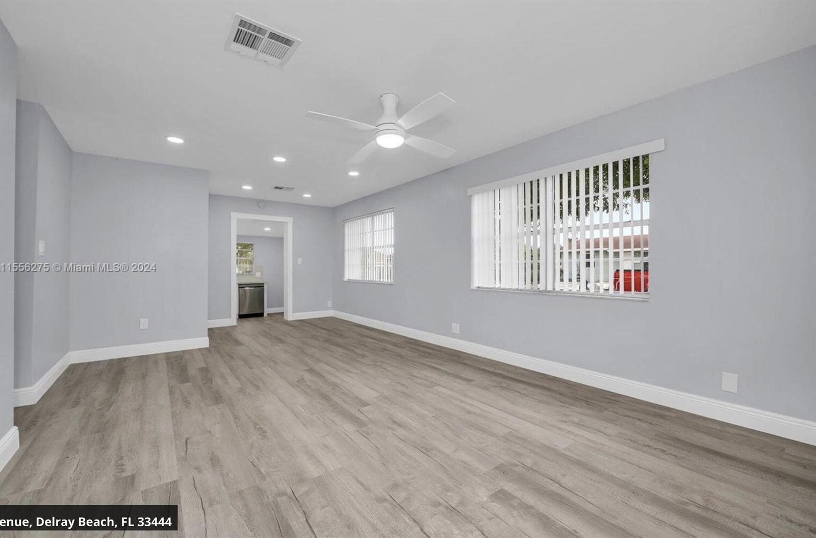 An empty room features light gray walls, wood-look flooring, recessed lighting, and vertical window blinds — 145 SW 13th Avenue, Delray Beach FL 33444, DELRAY BEACH, FL