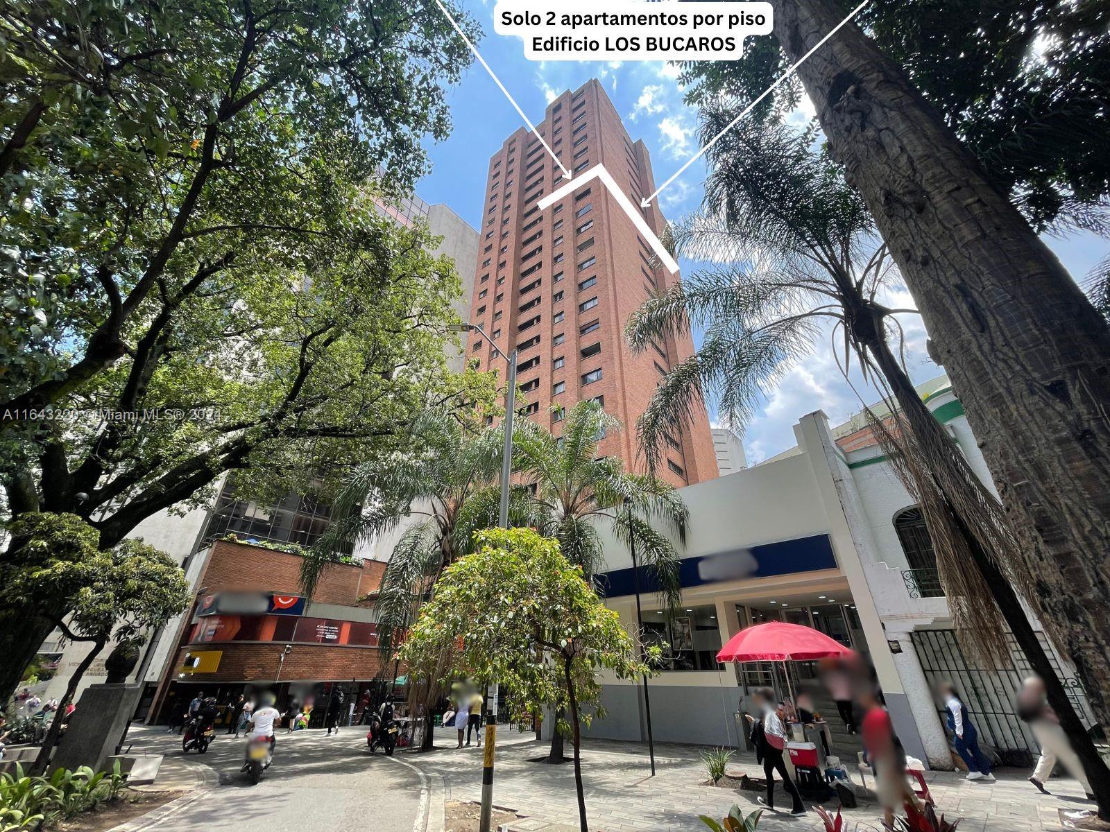 A tall red brick apartment building stands behind trees and a street-level commercial area — Calle 52 45-44 # 2001, CO, CO