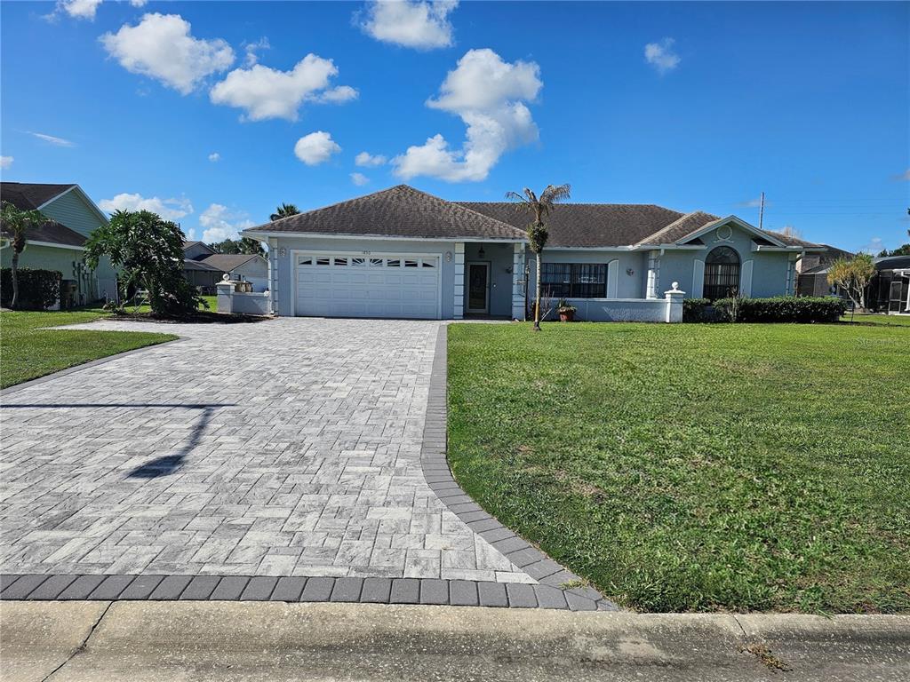 A single-story house with a paved driveway, a two-car garage, and a large front lawn — 1850 CHAUCER WAY, KISSIMMEE, FL