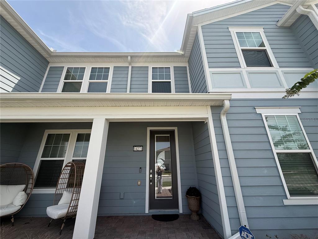 The exterior of a two-story blue house features a covered porch and a glass-paneled door — 14271 LANIKAI BEACH DRIVE, ORLANDO, FL