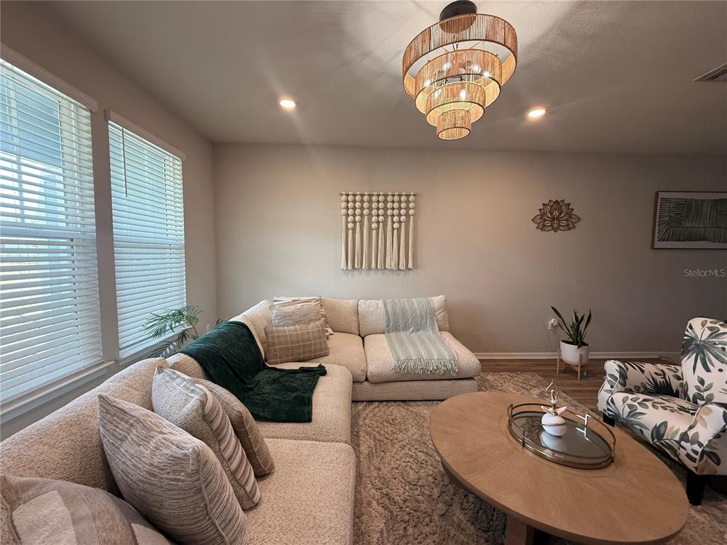 A living room features a beige sectional sofa, a round coffee table, and a tiered chandelier — 14271 LANIKAI BEACH DRIVE, ORLANDO, FL