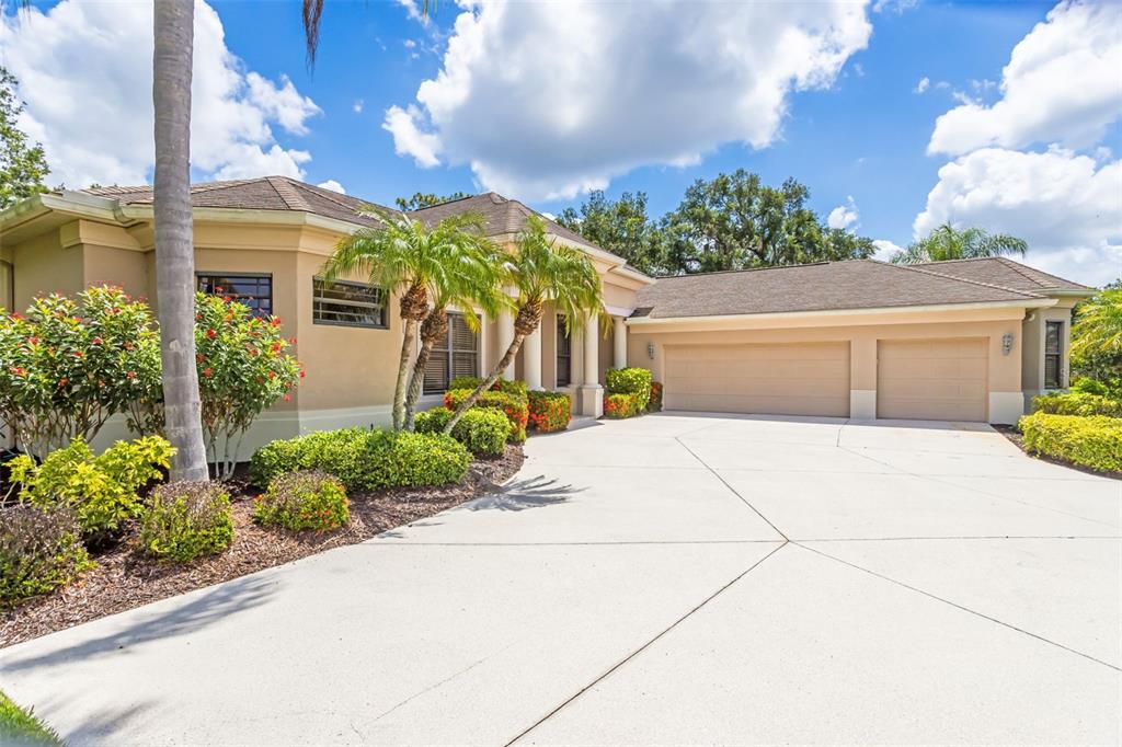 A single-story house with a tan stucco exterior, a three-car garage, and a concrete driveway — 2339 LITTLE COUNTRY ROAD, PARRISH, FL